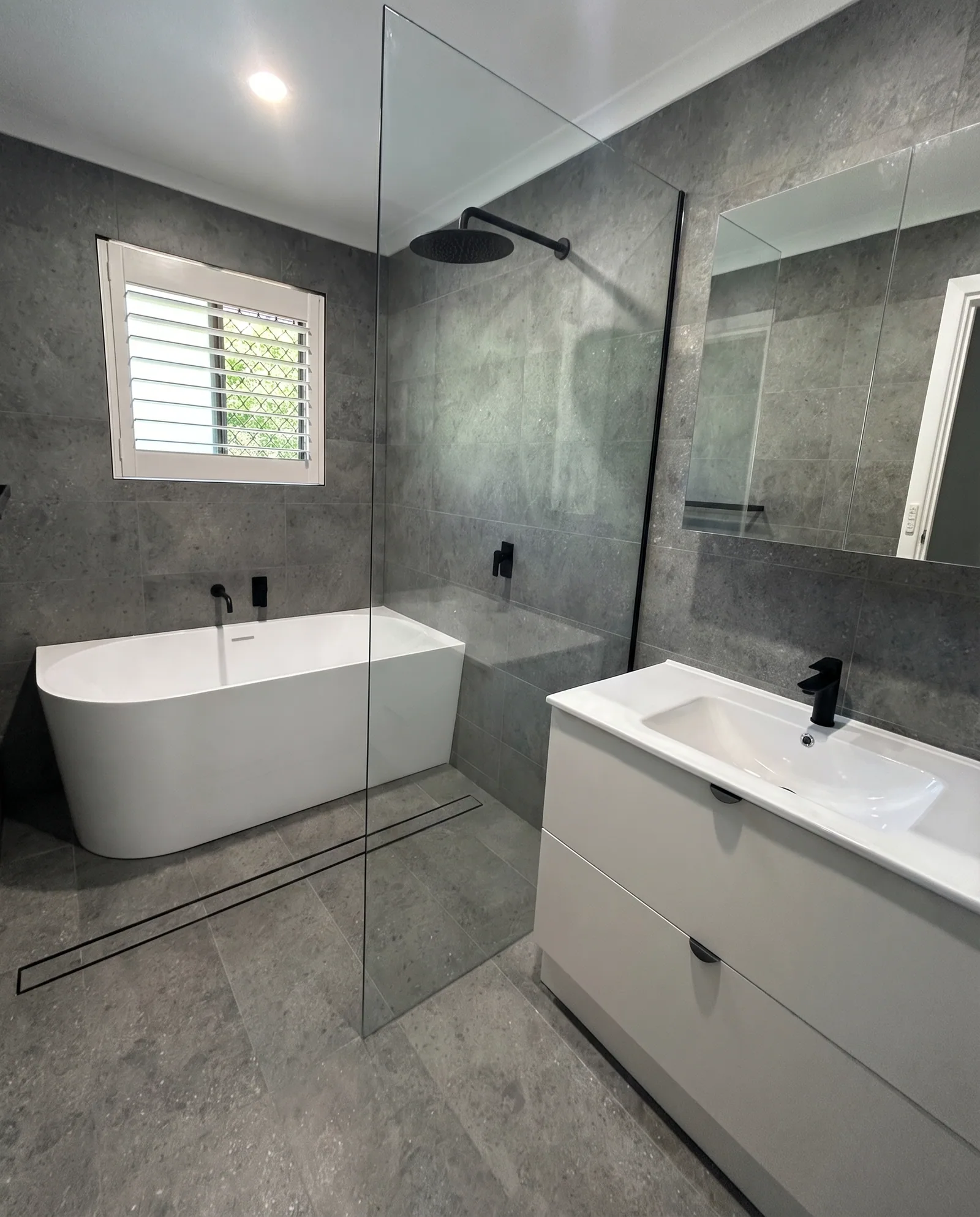 Grey tile bathroom with freestanding tub